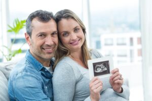 Portrait of couple sitting on sofa and holding ultrasound scan